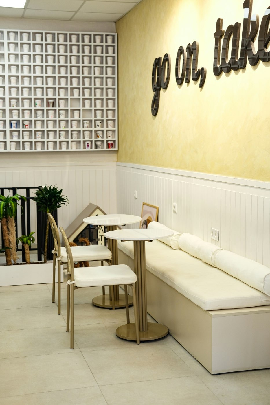 Bright modern cafe interior with white seating and wall-mounted cups in Amman