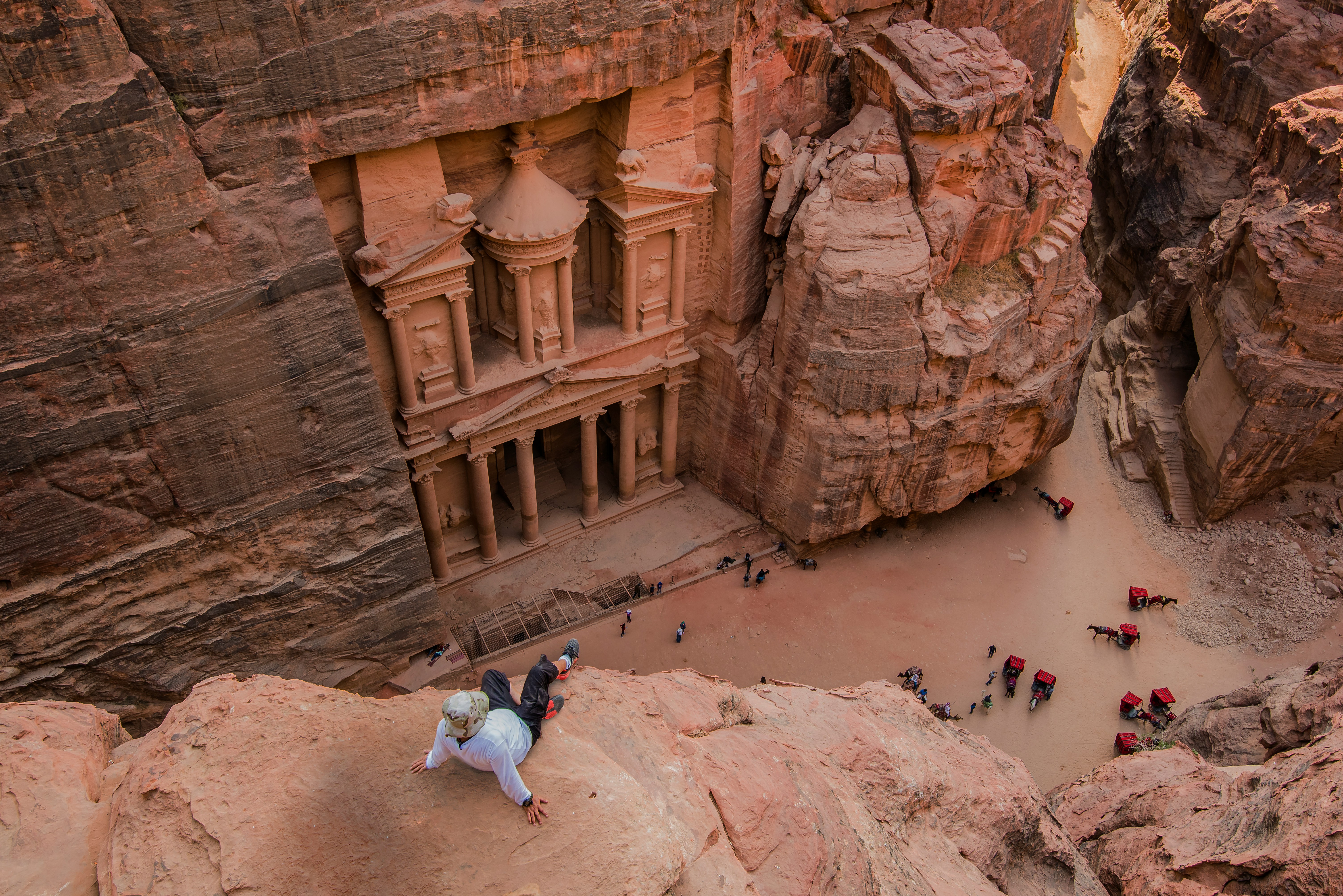Aerial view of Petra Treasury with visitors descending the rocky path from above, Jordan
