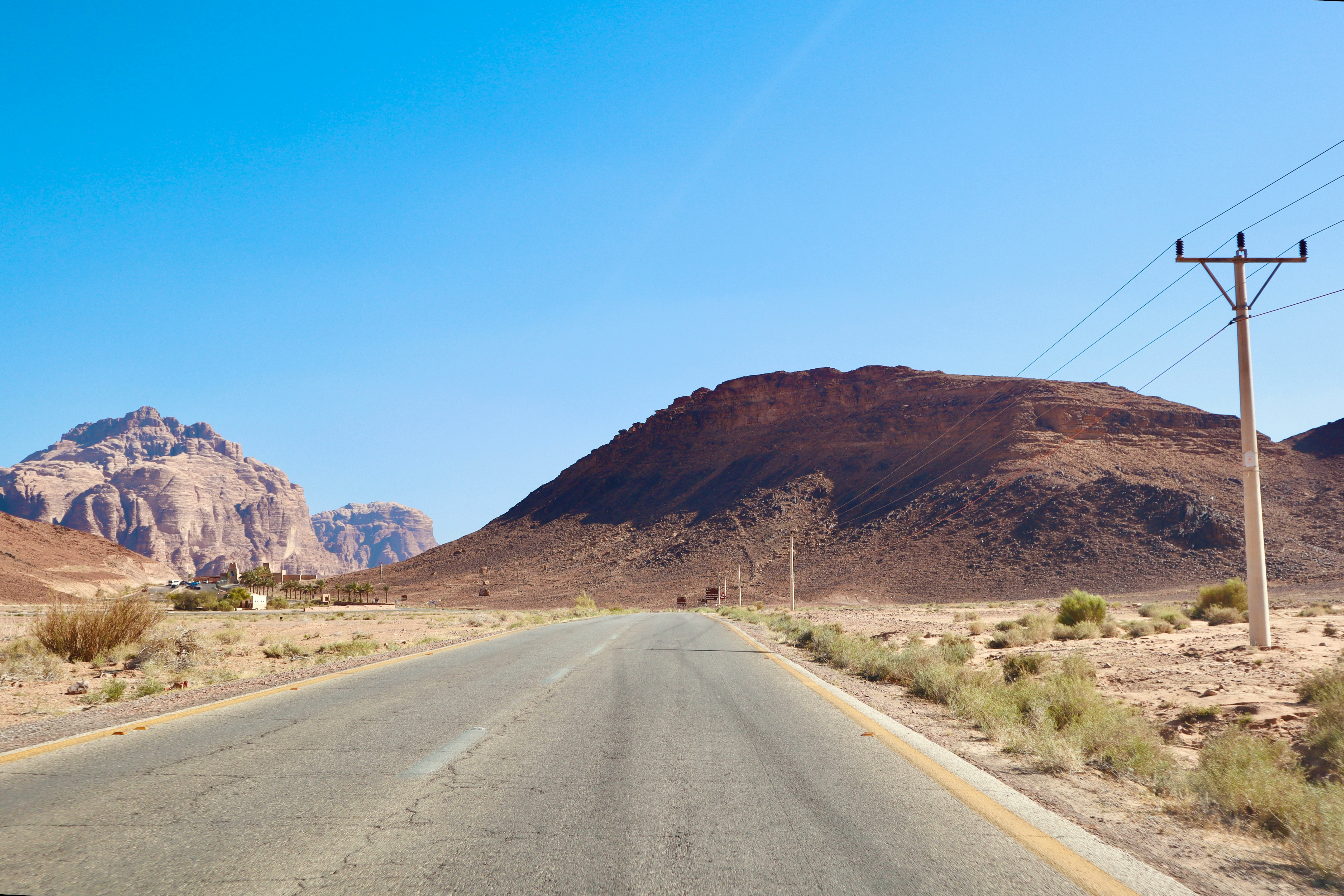 Desert highway road stretching through a rocky Jordan landscape with mountains in the background