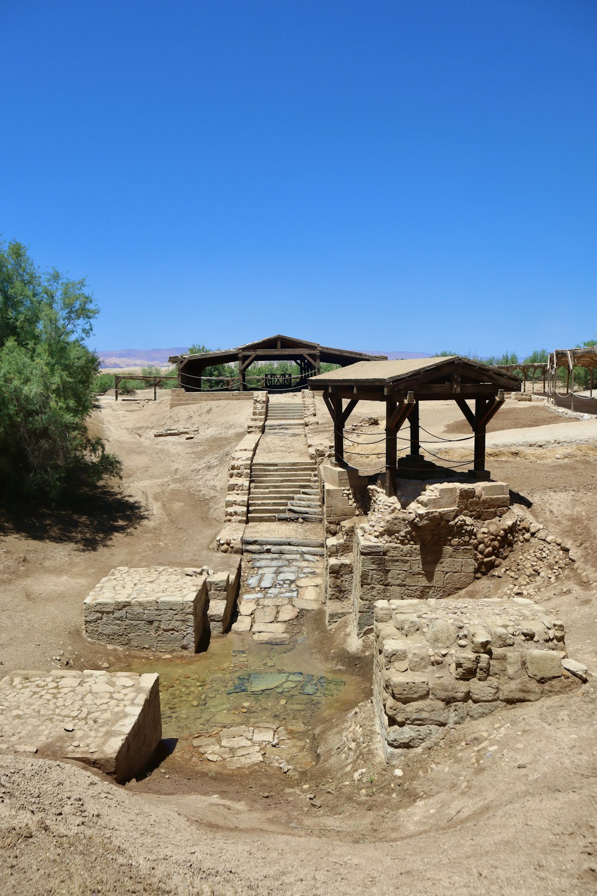 Ancient stone baptism pool steps descending into water at Al-Maghtas, Bethany Beyond the Jordan