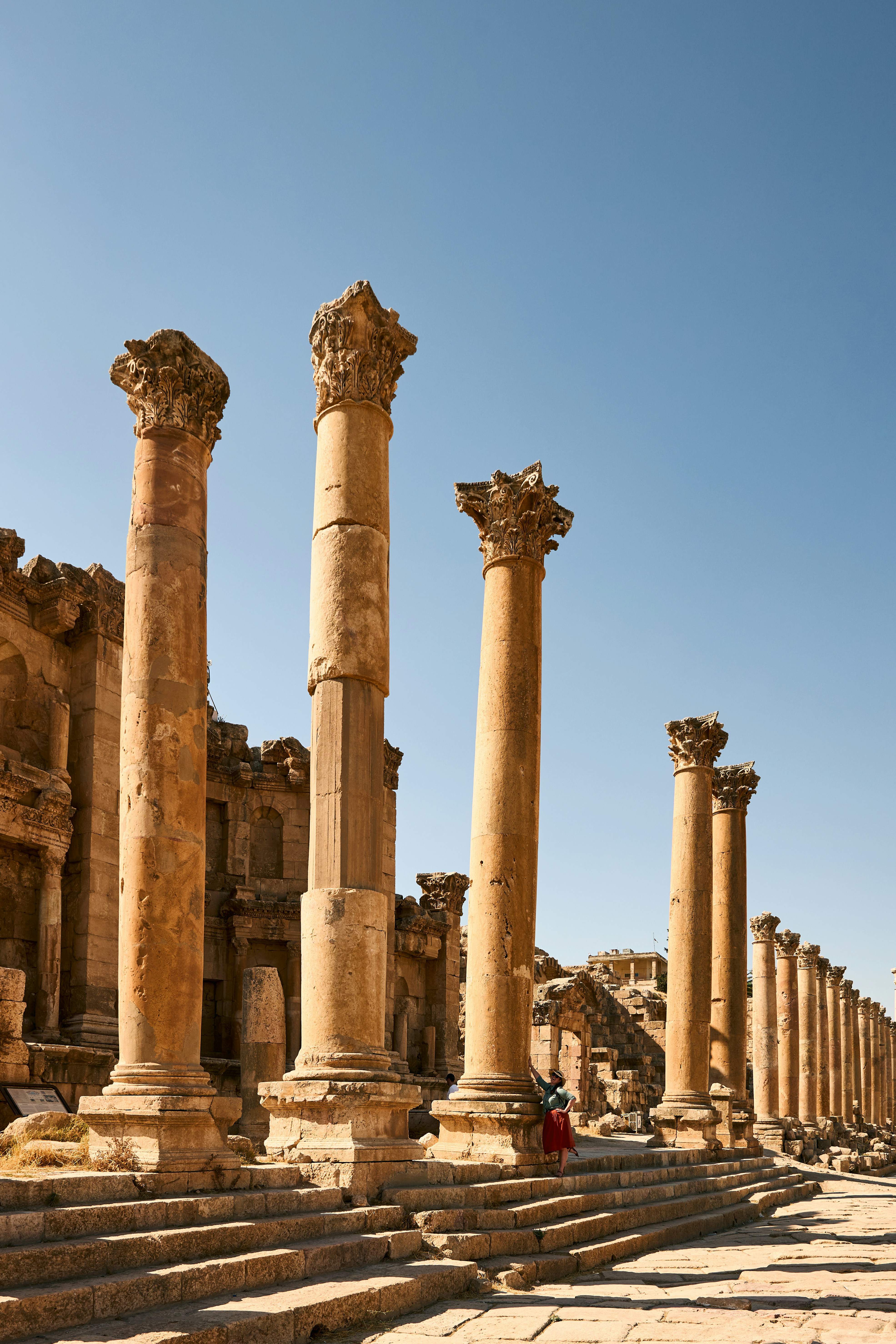 Tall Roman columns lining the Colonnaded Street at Jerash under a clear blue sky