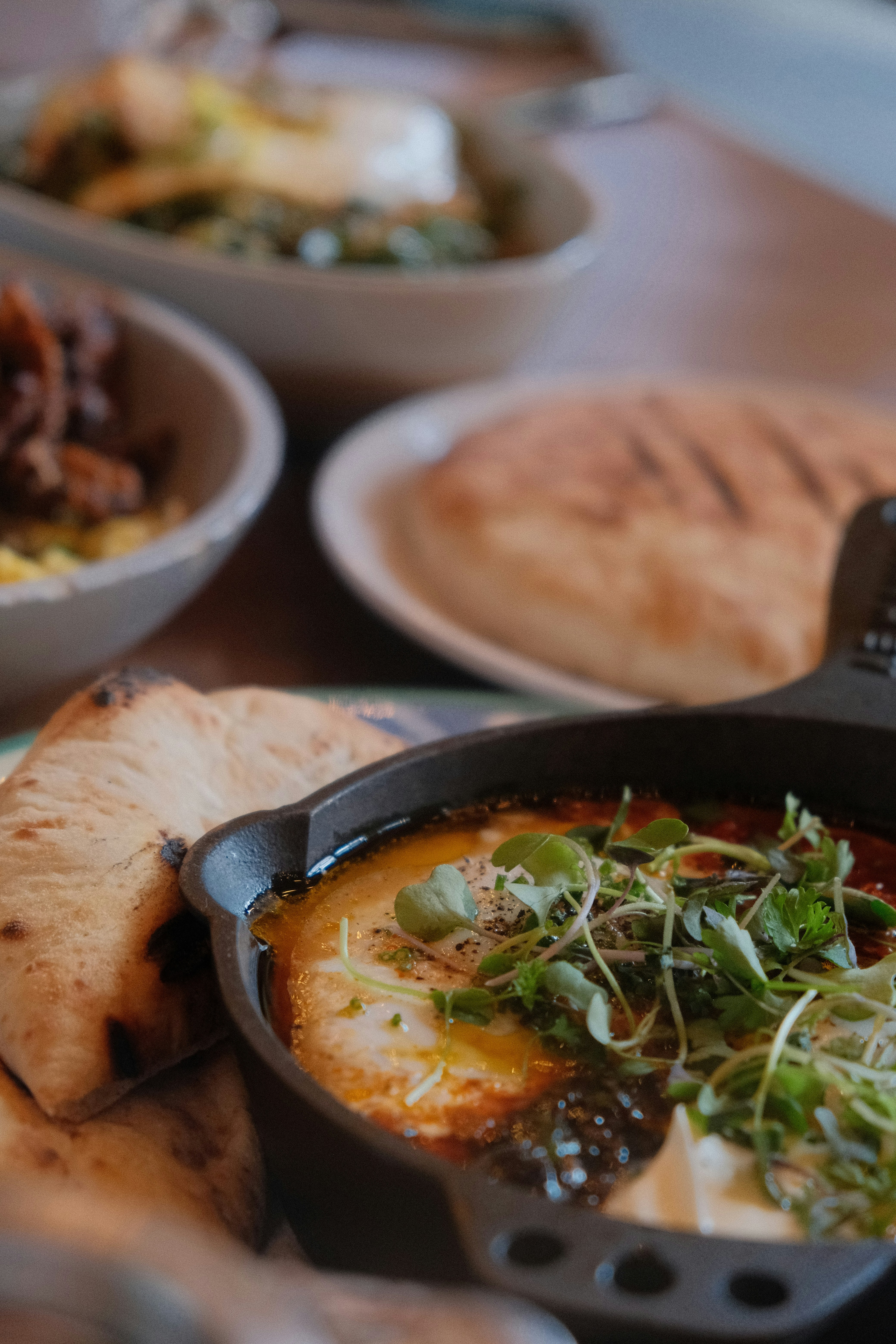 Shakshuka baked eggs in a cast iron pan with pita bread — Middle Eastern cooking class spread