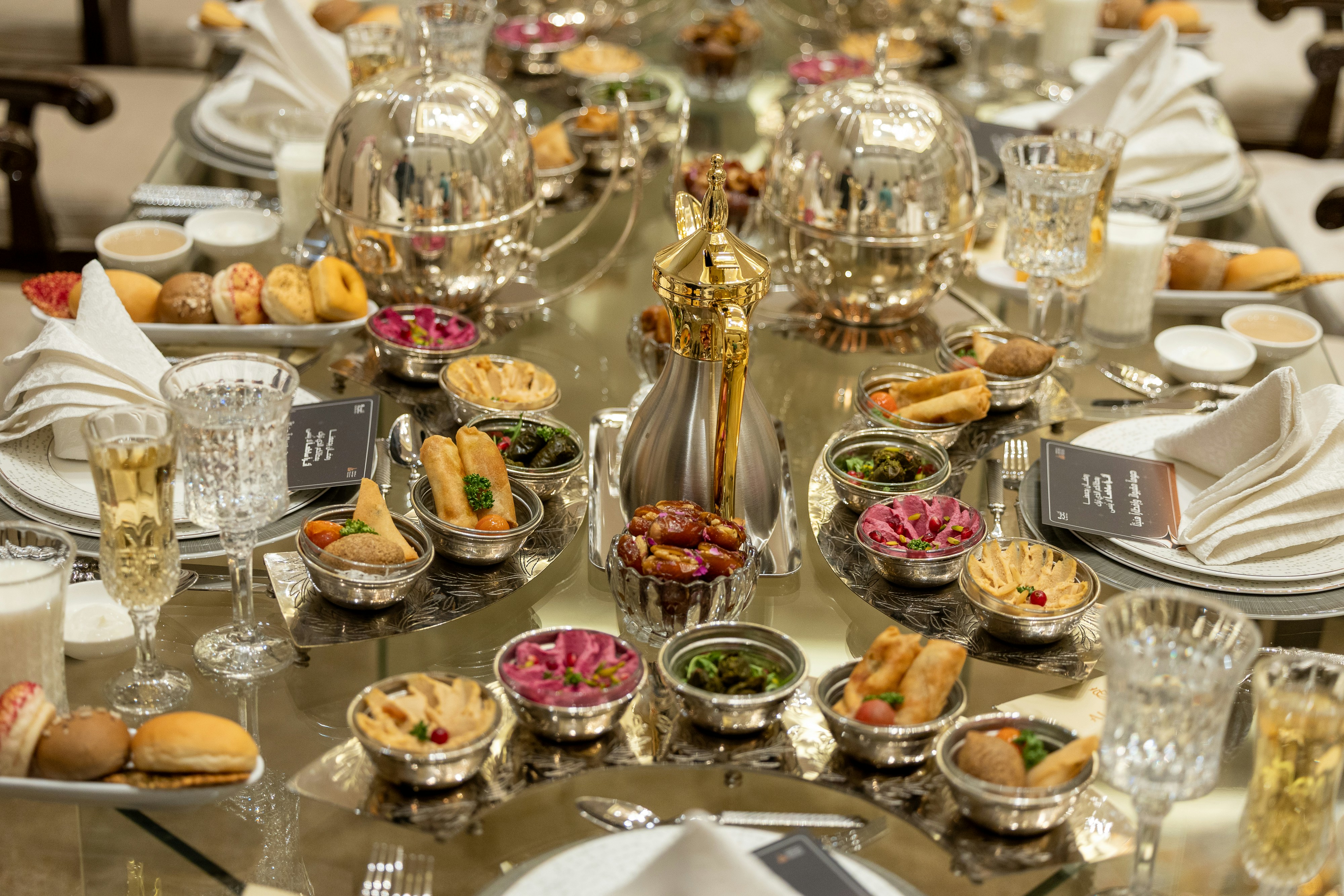 Elegant dining table setting with silver cloche covers, mezze dishes, and crystal glassware at a Dead Sea resort restaurant