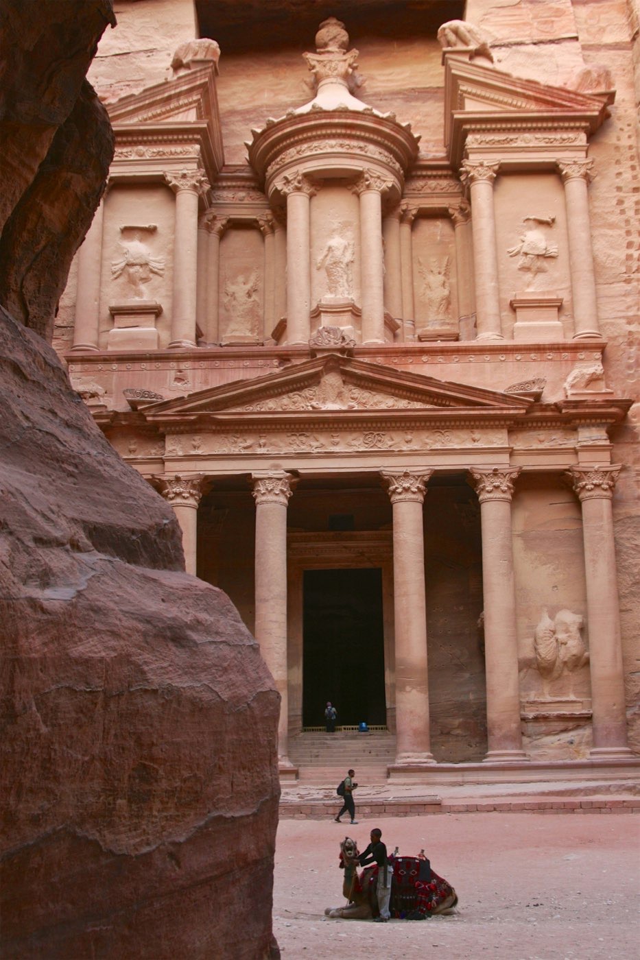 The Petra Treasury carved into sandstone cliffs with a camel resting in the forecourt