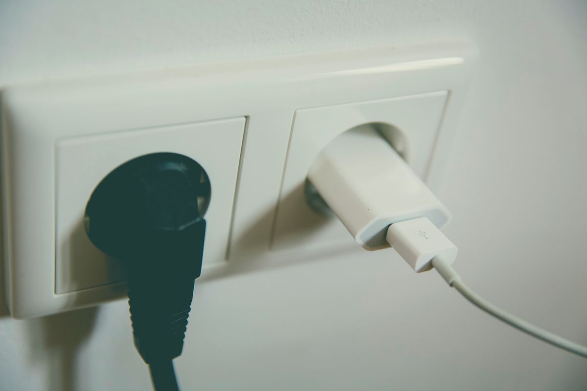 Two plugs inserted into a white double wall outlet, illustrating the plug types used in Jordan