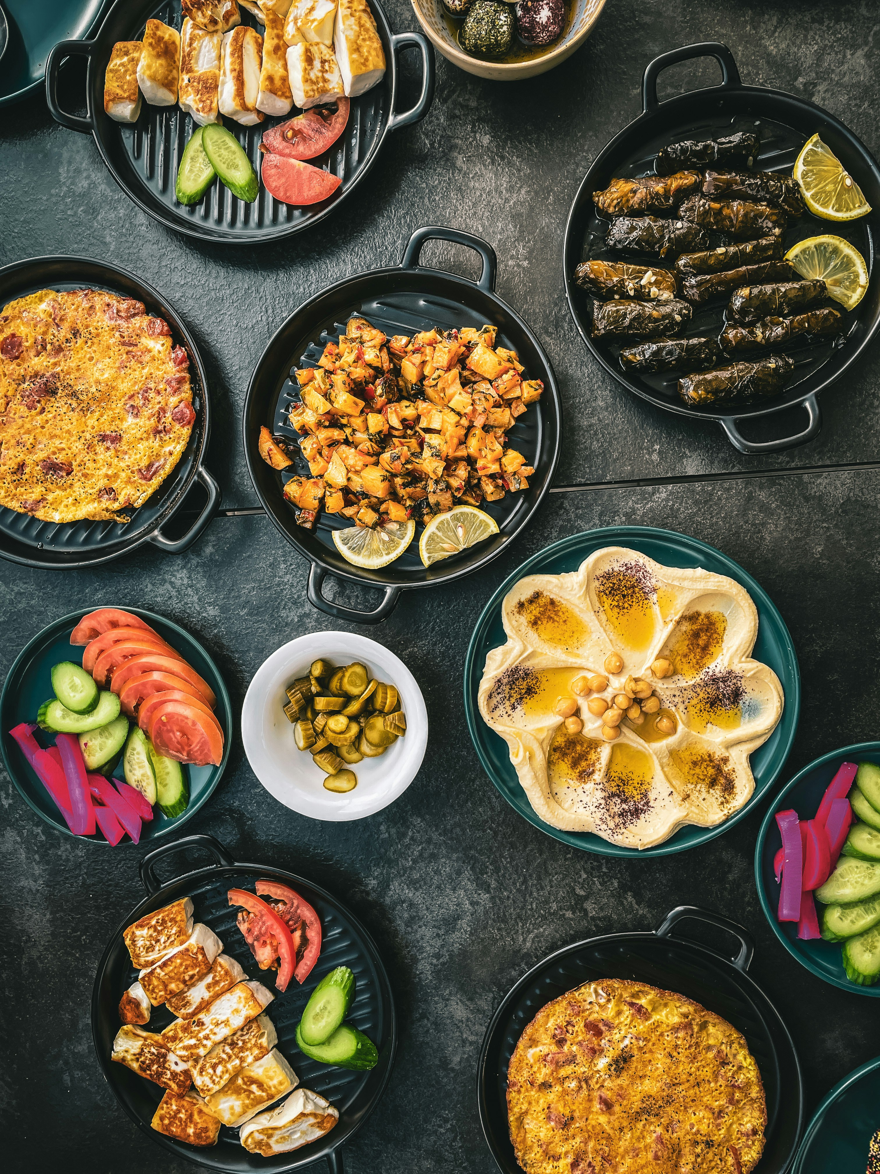 Spread of Middle Eastern dishes including hummus, grilled halloumi, stuffed vine leaves, and salads at a Jordanian restaurant