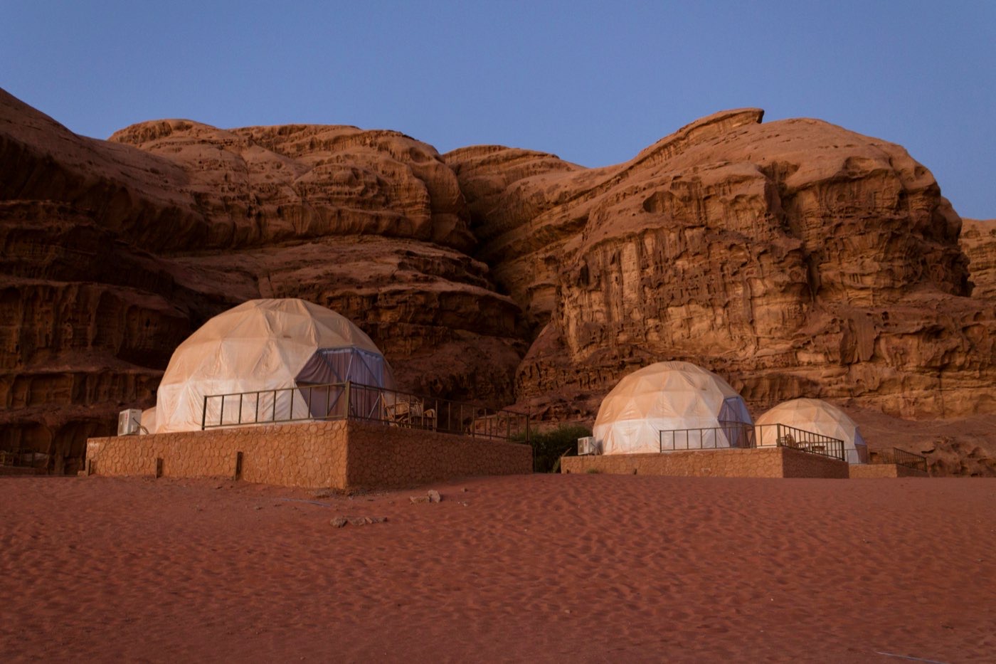 Dome glamping tents nestled against red sandstone cliffs in Wadi Rum, Jordan