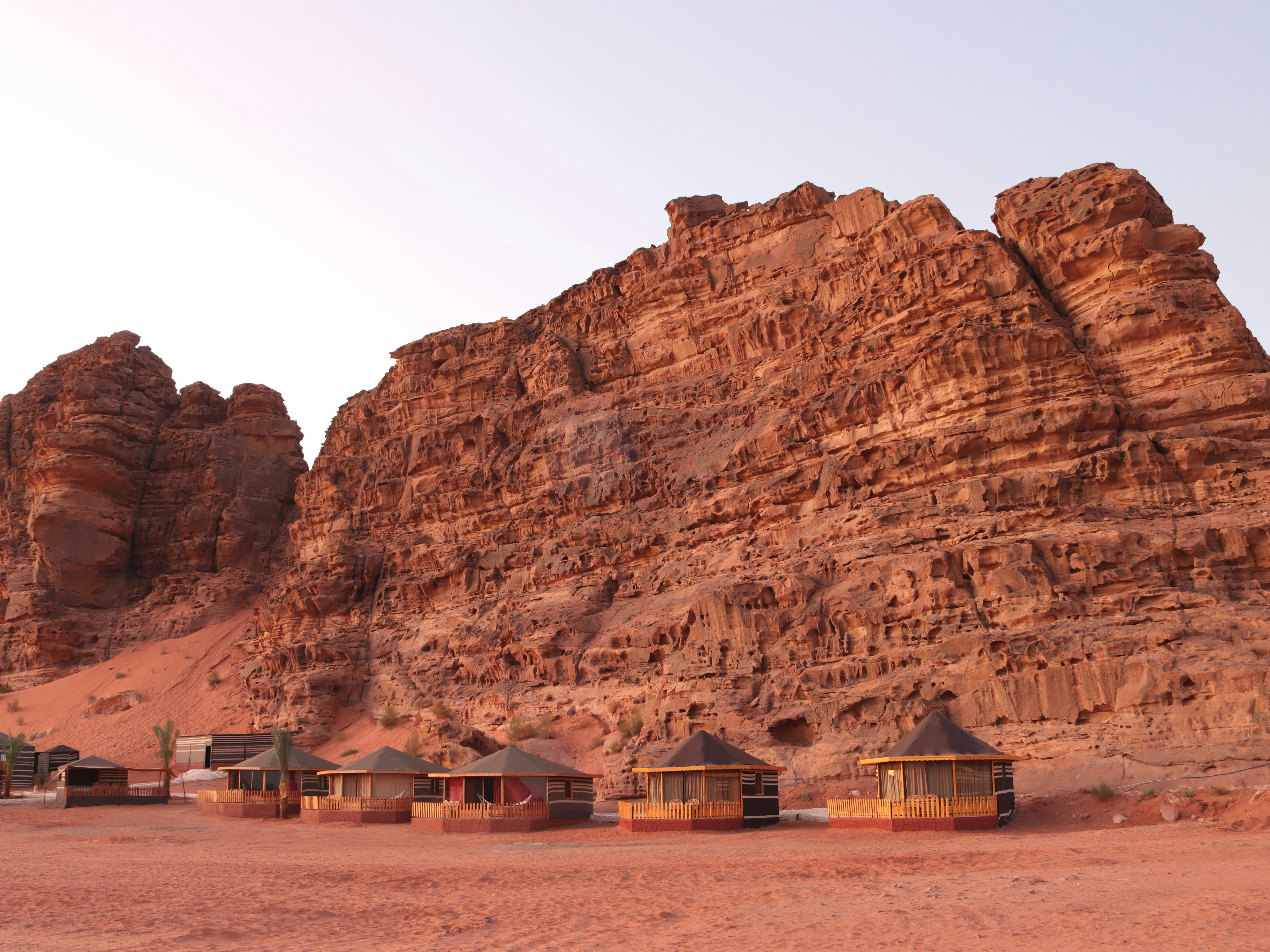 Traditional circular Bedouin camp huts at the base of red sandstone cliffs in Wadi Rum Protected Area, Jordan