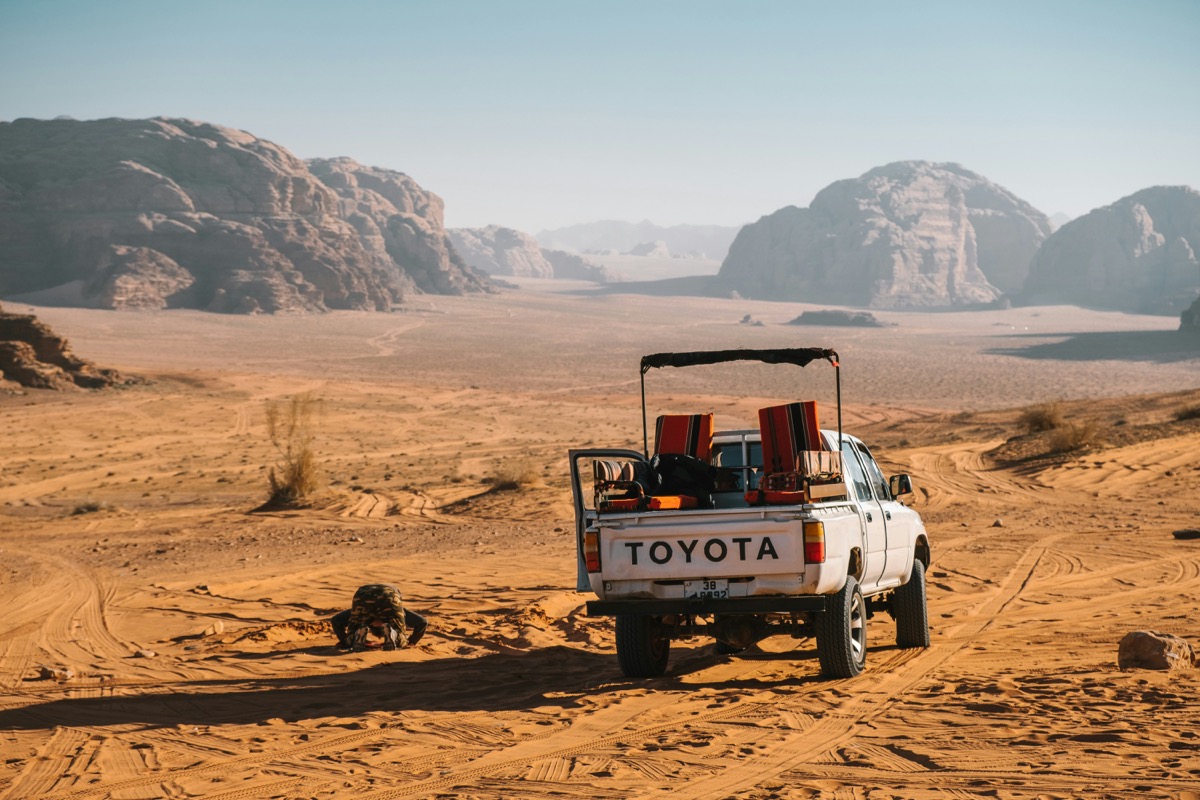 White 4x4 pickup truck driving through red sand desert in Wadi Rum, Jordan